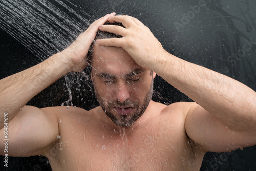 Man taking morning shower. Washing hair under water falling from shower head. Close up guy showering. Body care hygiene. Shower concept. Man is under water drops in shower. Wellness and spa.