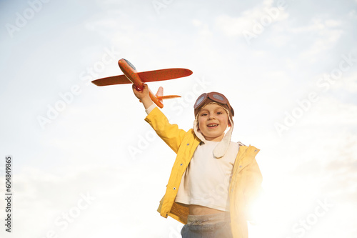 Against cloudy sky. Little boy is playing with toy plane on the summer field © standret