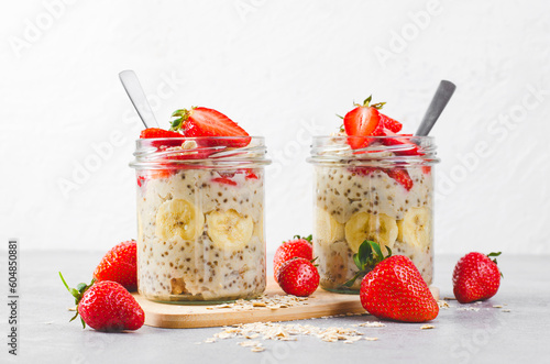 Overnight Oats with Fresh Strawberry, Banana and Chia Seeds in Jars on Light Grey Background, Healthy Snack or Breakfast