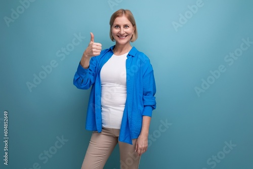 mature woman shows her hands in different directions on a blue background with copyspace
