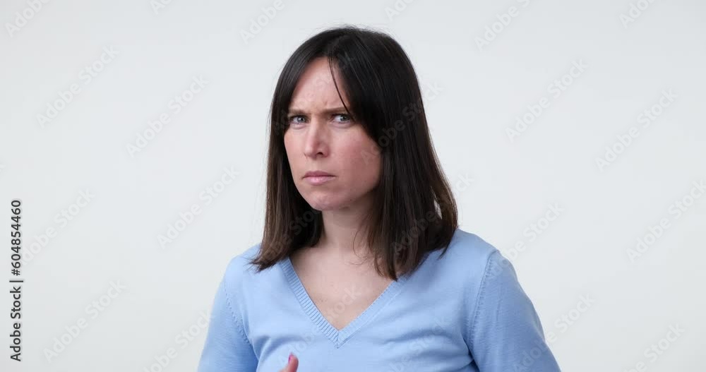 A Caucasian woman stands on a white background and looks directly at the camera. Suddenly, she becomes startled and frightened, showing a reaction of fear. A Caucasian woman stands on a white background and looks directly at the camera. Suddenly, she becomes startled and frightened, showing a reaction of fear.
