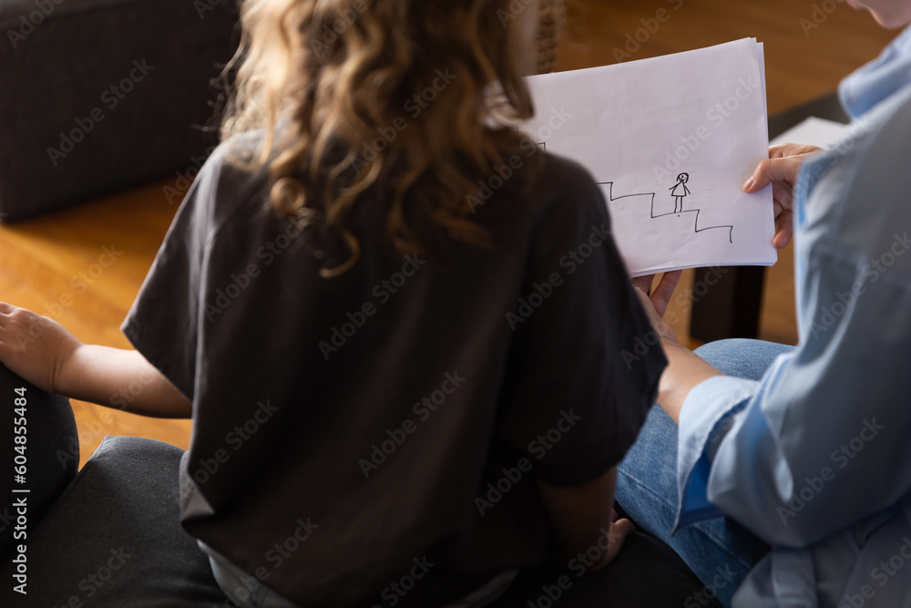 A girl at a psychologist's appointment draws a test drawing, low self-esteem and psychological problems in a child, a photo from the back