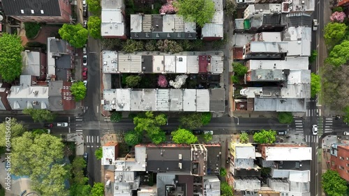 Aerial descending shot of urban city in spring. Flowering and blooming trees surround row houses in downtown. Establishing shot of housing in springtime. photo