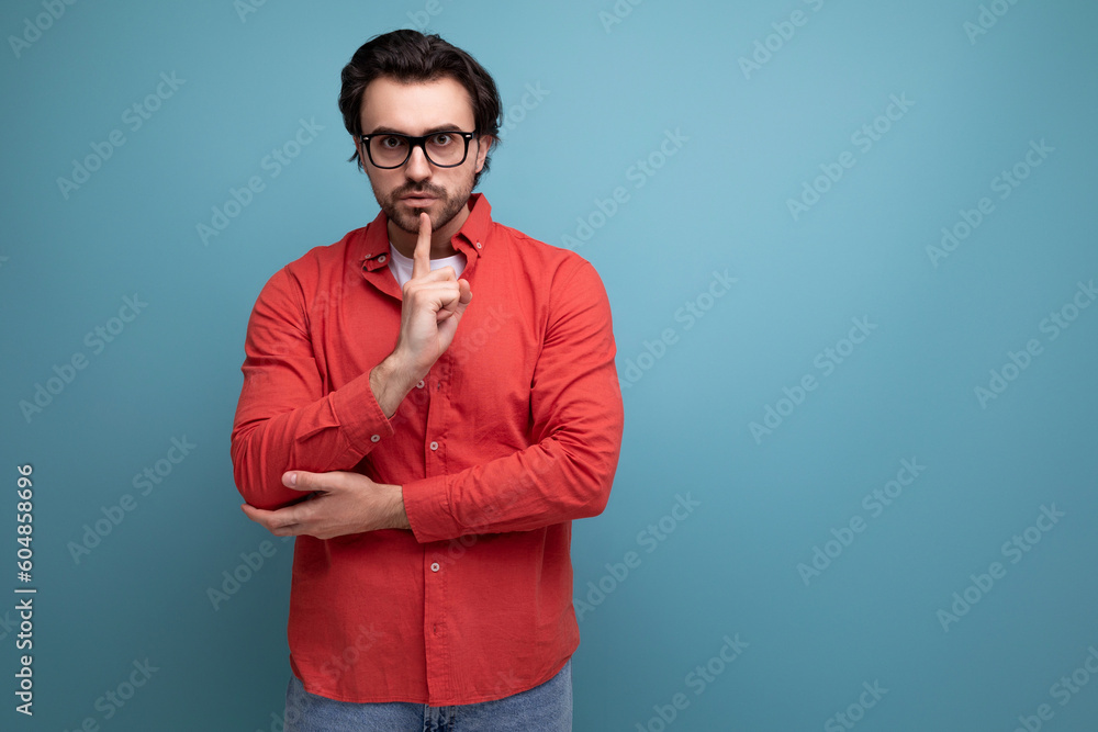 Fototapeta premium smart handsome young brunette man in glasses and a red shirt on the background with copy space