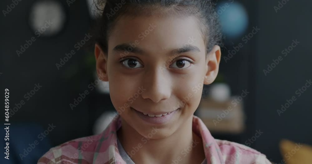Close-up portrait of cheerful Middle Eastern girl smiling feeling happy looking at camera at home. Childhood and happy face expression concept. Close-up portrait of cheerful Middle Eastern girl smiling feeling happy looking at camera at home. Childhood and happy face expression concept.