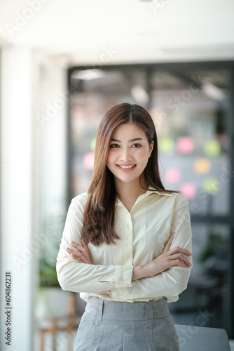 Charming Asian woman with a smile looking to the camera in the office. Free Download Charming Asian woman with a smile looking to the camera in the office. - GFXLoad