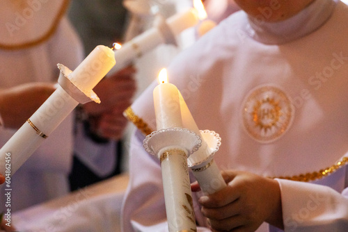 children distribute fire from candles of peace candles to other candles at first communion