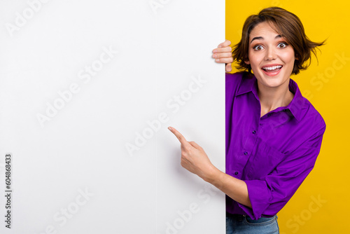 Portrait of cheerful person direct finger empty space billboard proposition isolated on yellow color background
