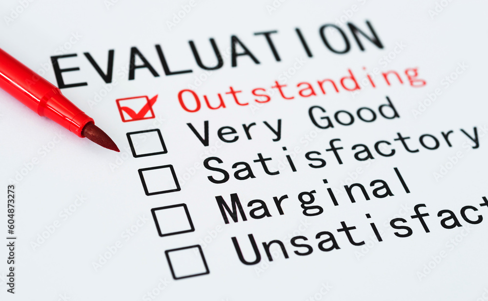 Pen checking the word Outstanding in a evaluation Pen checking the word Outstanding in a evaluation