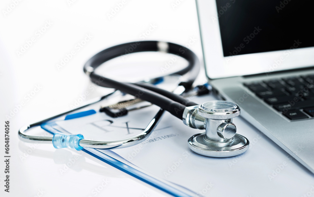 Stethoscope with clipboard and laptop on desk Stethoscope with clipboard and laptop on desk