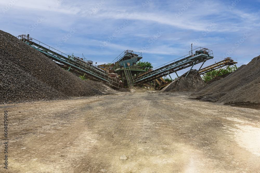Crushing machinery, cone type rock crusher, conveying crushed granite gravel stone in a quarry open pit mining..