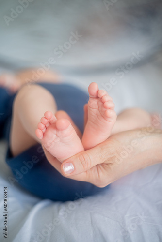 Close up of a woman's hand holding baby's legs.