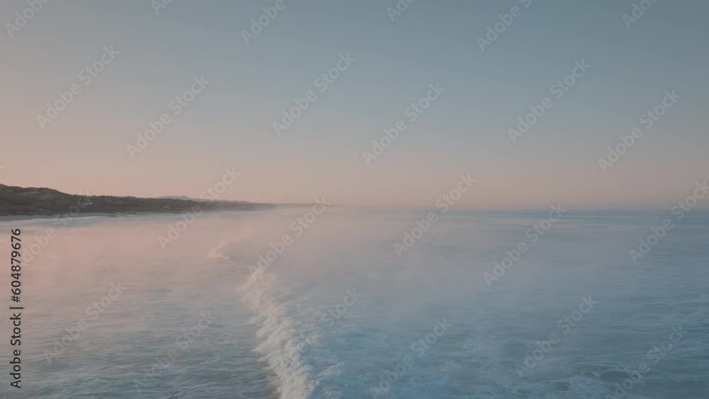 Pink sunset sky over blue ocean waves. Foamy waves rolling towards the beach. Seaside sunset colours and beautiful nature. Pink sunset sky over blue ocean waves. Foamy waves rolling towards the beach. Seaside sunset colours and beautiful nature.