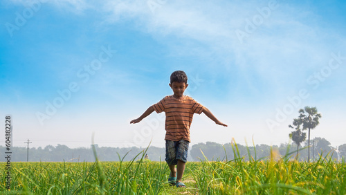 A child dances with nature on a rural path. Children in the village of Bangladesh play in the field.
