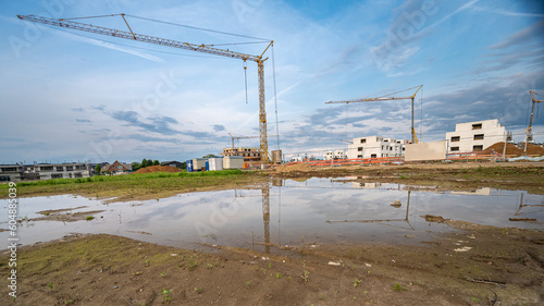 Neubaugebiet mit Häusern und Baumaschinen und Spiegelung