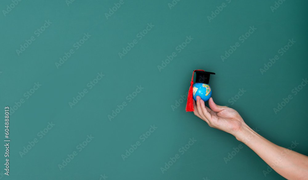 Hand hold a globe and mortarboard in front of blackboard - obrazy, fototapety, plakaty 