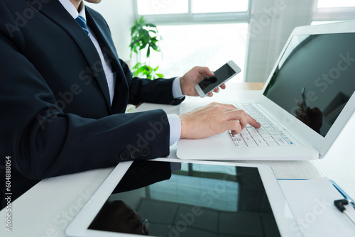 Businessman in office using laptop, tablet and smart phone on the desk