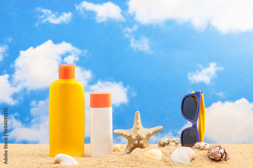 Summer vacation at sea and sun protection. Sand, shells, sunglasses and two tubes of sunscreen.