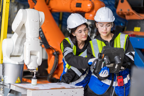 A team of female engineers meeting to inspect computer-controlled steel welding robots. Plan for rehearsals and installation for use.