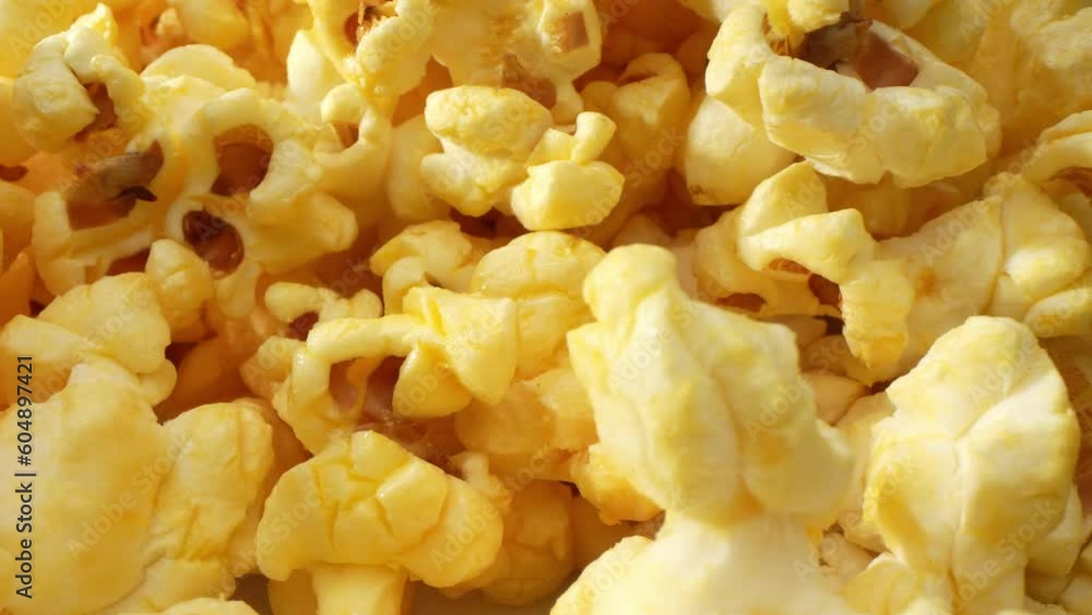 A macro video shot with a probe lens, scattered popcorn on the floor becomes a captivating spectacle. offering a unique perspective. Shot by Laowa 24mm Probe Macro Lens. Snack and food concept. 4K
