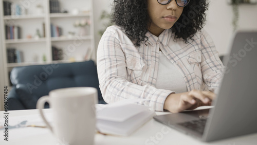 African American woman working on her laptop from home as a freelancer in a part-time job