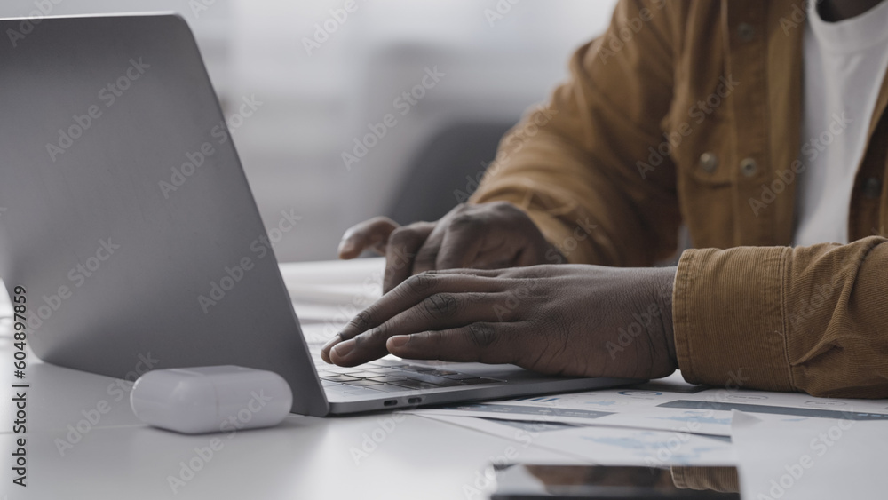 Close-up of African American man typing on laptop at home, remote work, freelance Close-up of African American man typing on laptop at home, remote work, freelance