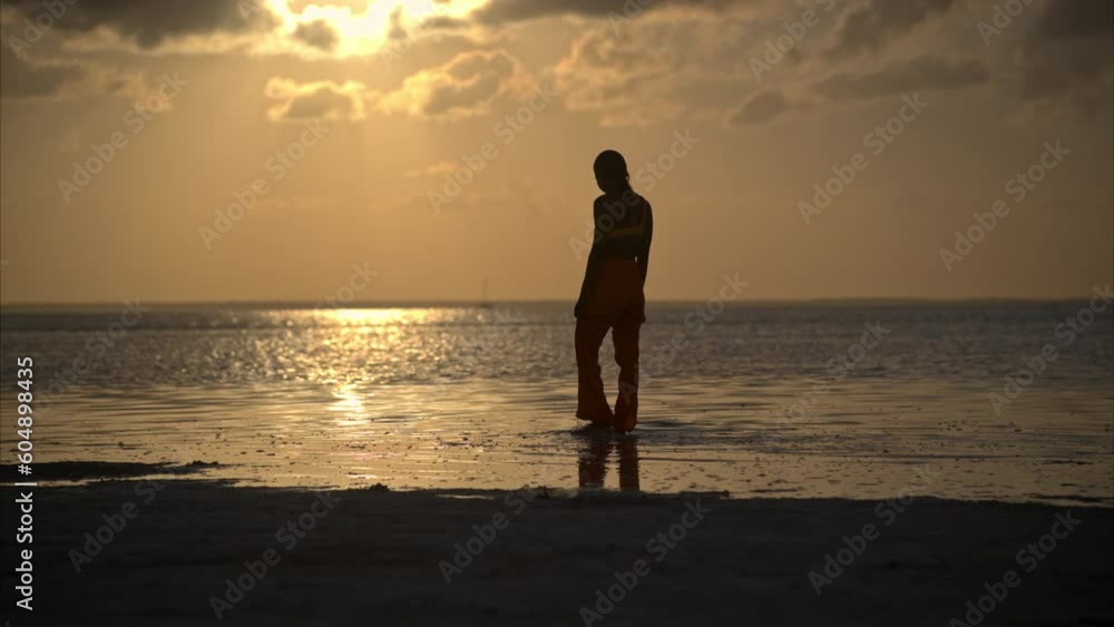 Graceful silhouette of a sexy latin woman enjoying the sunset walking on the shallow waters of a dreamy beach in Cancun Mexico Graceful silhouette of a sexy latin woman enjoying the sunset walking on the shallow waters of a dreamy beach in Cancun Mexico