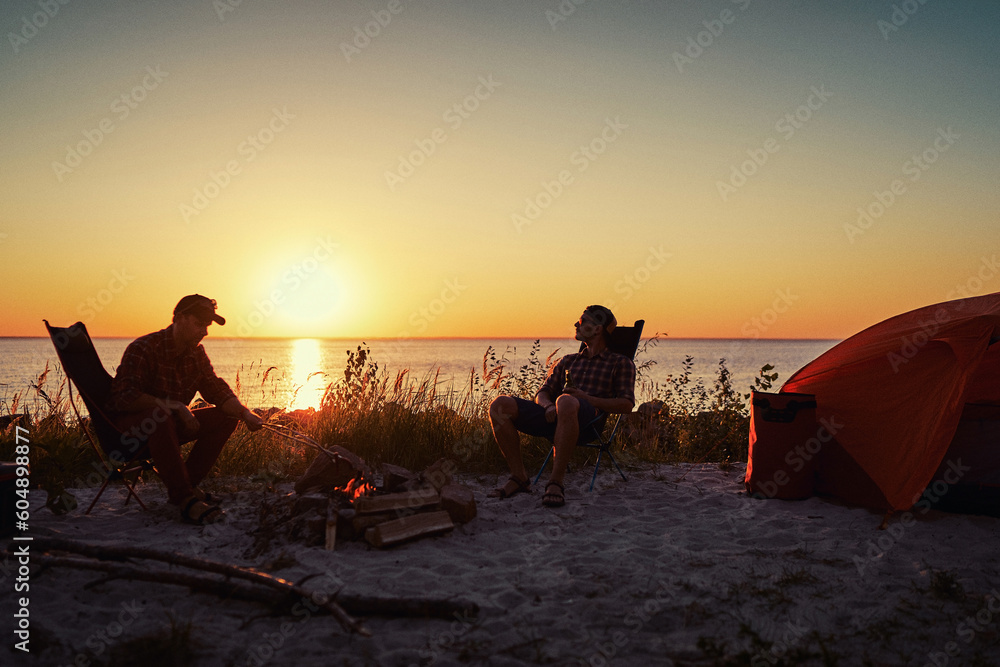 Happy young friends enjoy a sunny day at the nature. They're toasting with beer bottles by the bonfire near tent. Happy young friends enjoy a sunny day at the nature. They're toasting with beer bottles by the bonfire near tent.