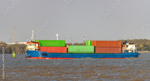 The cargo vessel loaded of containers sails along the coast photo