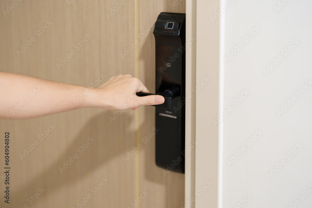 Hand using smart digital door lock while open or close the door at home or apartment. NFC Technology, Fingerprint scan, keycard, PIN number, smartphone, electrical and contactless lifestyle concepts Hand using smart digital door lock while open or close the door at home or apartment. NFC Technology, Fingerprint scan, keycard, PIN number, smartphone, electrical and contactless lifestyle concepts