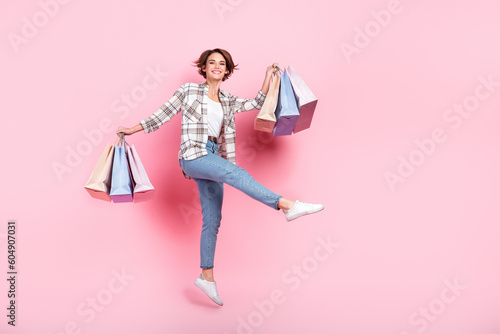 Full body photo of young careless girl jumping shopaholic hold much bargains new zara massimo dutti brand sale isolated on pink background photo