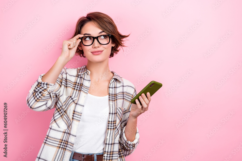 Portrait of thoughtful clever business lady wear plaid shirt smartphone looking interface new website options isolated on pink background - obrazy, fototapety, plakaty 