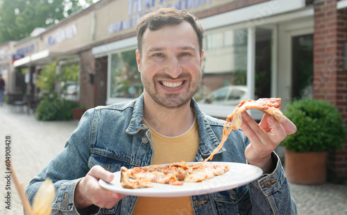 Close-up of young man eating pizza while sitting in restaurant.