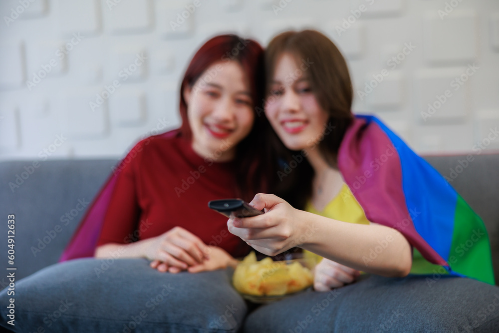 Female couple enjoying time together on a sofa. watching the television with a bowl of snack. Female couple enjoying time together on a sofa. watching the television with a bowl of snack.