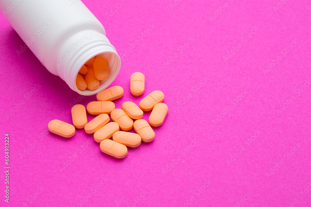 White medical tablets and pills spilled out of a medicine bottle. Macro top down view White medical tablets and pills spilled out of a medicine bottle. Macro top down view