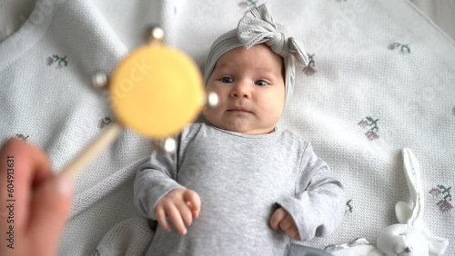 Young dad and baby daughter playing with rattle toy. New father nursing little two month child at home. Baby care and parenthood concept