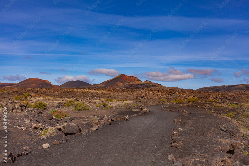 Winding road leading to the mountains. Sandy-clay soil. Mountain landscape under white clouds.