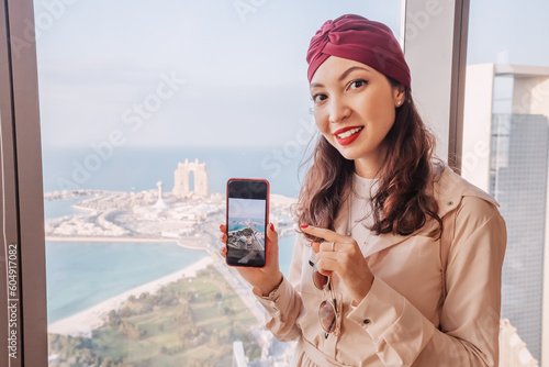 Photography Indian girl travel blogger taking photos on her smartphone from height of a roof