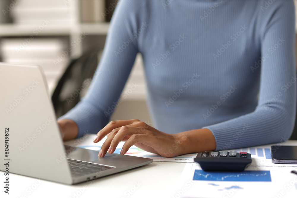 Naklejka premium Businesswoman working with laptop and financial documents on desk, financial and investment data analysis, financial planning and accounting.