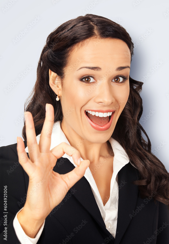 Excited smiling positive businesswoman wear black confident suit show make ok okay hand sign, isolated on light grey gray wall background. Happy gesturing brunette woman. Business success ad concept. Excited smiling positive businesswoman wear black confident suit show make ok okay hand sign, isolated on light grey gray wall background. Happy gesturing brunette woman. Business success ad concept.