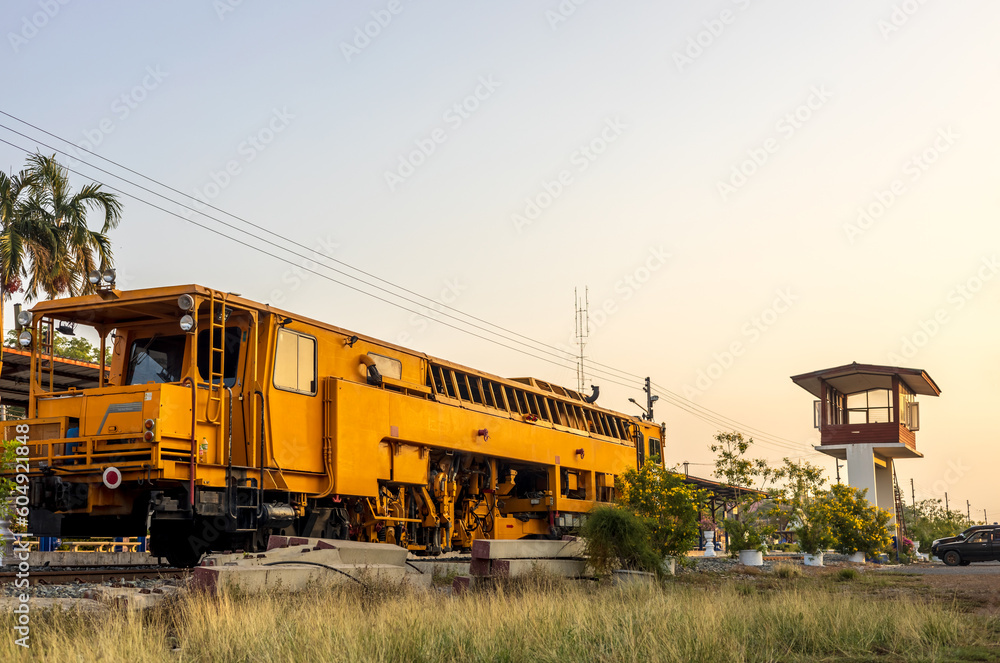 Low angle view of yellow train stationary on grassy track near station.