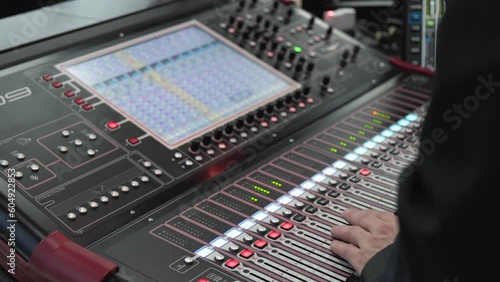 A sound engineer works on his sound mixing board at an event - closeup photo