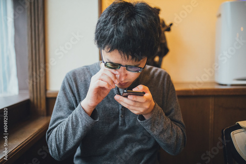 グレーの服を着た視覚障害者の男性がスマホを使っている