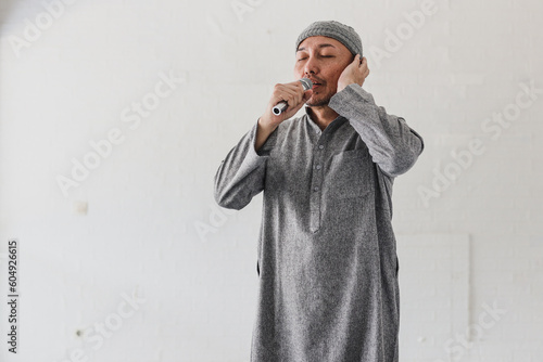 Valokuva Muslim man with doing azan or iqamah isolated over white background
