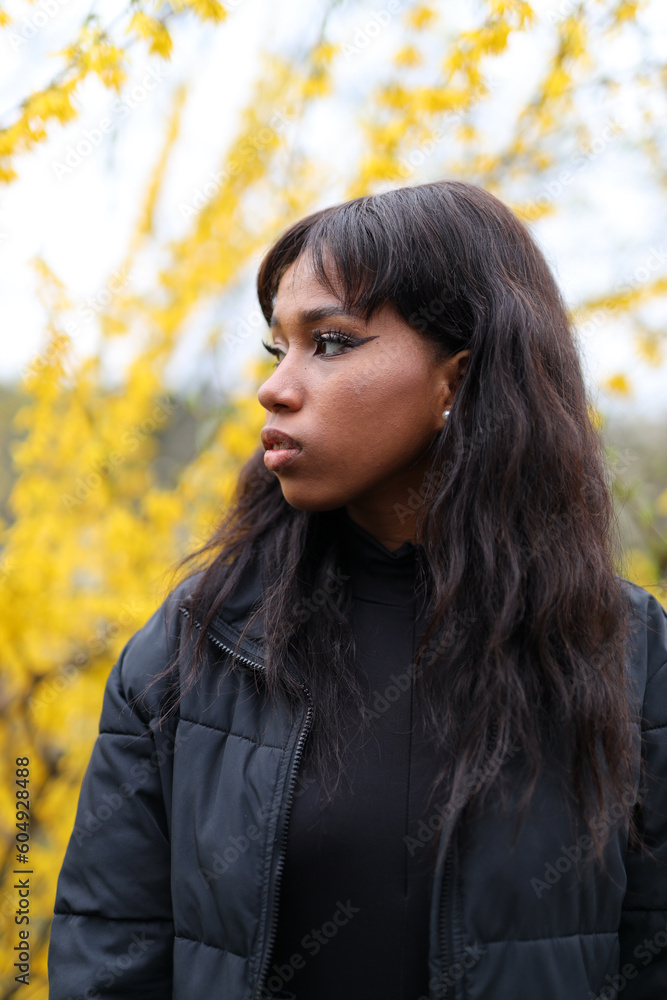 Dark-skinned girl looks to the side in a blooming yellow park, portrait Dark-skinned girl looks to the side in a blooming yellow park, portrait