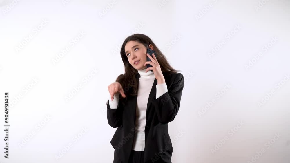 Engaged young female with expressive body language in formal wear with dark hair against white background talking on her smartphone and finishing the call Engaged young female with expressive body language in formal wear with dark hair against white background talking on her smartphone and finishing the call