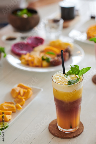 Big glass of cold beverage decorated with mint leaves on brunch table