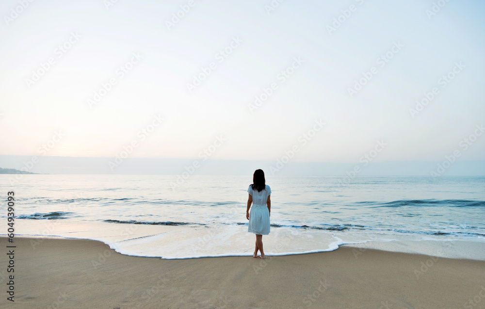 Young asian woman relaxing on the beach at sunrise.