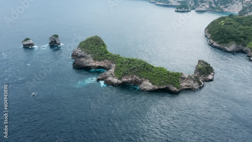 A view from a flying plane height of a lonely beautiful elongated tropical island with rocky shores in the ocean. Flying around island washed by a strong sea current and fishing boat. Drone copter. photo