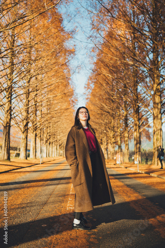公園で秋を感じているコートを着た難病を持った日本人女性